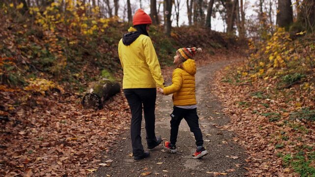 Mother and son walking on the autumn forest path.