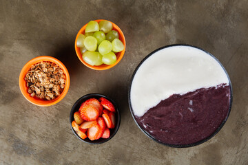 Açaí and Cupuaçu on a bowl with strawberry and grape over a stone background