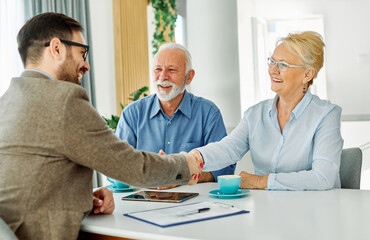 Portrait of a businessman or real estate agent or doctor shaking hands and signing a deal contract...