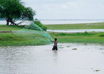Fisherman holding fish net to caught fish in the lake net at the coast of Ban Tha rit campground as know as New Zealand in Thailand in Lopburi Province, Thailand.