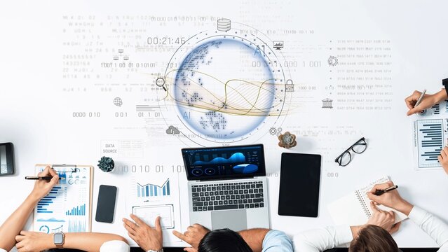 A dynamic modern office workspace featuring a laptop, charts, global data visualization, and teamwork for analysis and strategic planning in a business environment. Raster