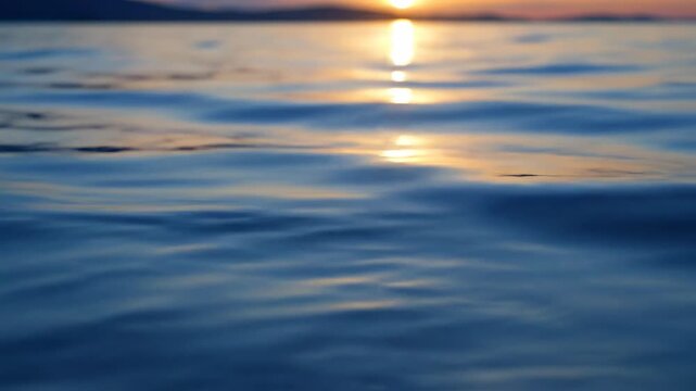Serene blue water surface reflecting a cloudless sky during golden hour with a gentle, hypnotic lapping motion dawn, relaxation, minimalist