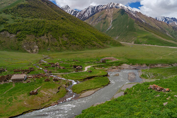 Abandoned stone hamlet along rushing river in high Caucasus valley