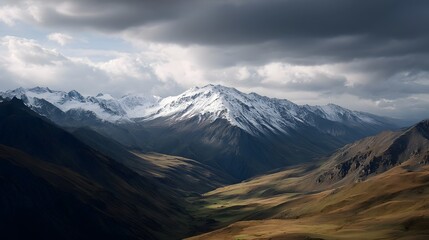 A majestic snow capped mountain range and valley under dramatic cloudy skies bathed in soft directional light