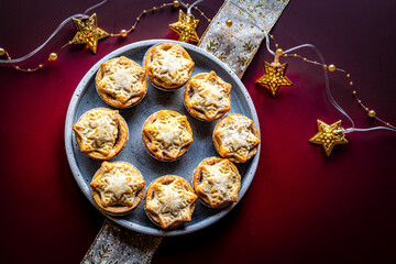 Christmas mince pies on a grey plate on a deep red background with Christmas lights