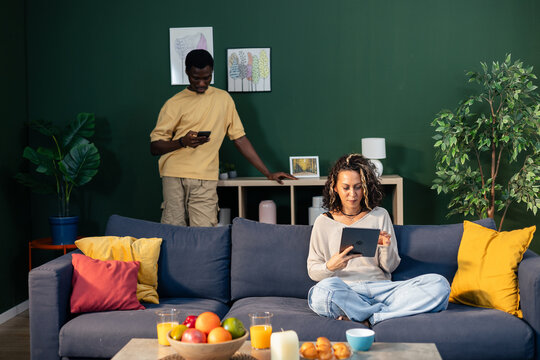 Diverse couple using technology relaxing at home