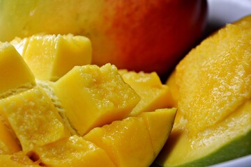 Macro close-up of a ripe mango hanging from a leafy tree branch, with dewdrops and golden skin glowing in natural sunlight. 