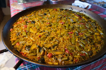Traditional Valencian paella with chicken and vegetables in a wide, vibrant setting with space for text
