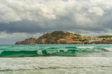Fototapeta premium Yacht gently rocking on turquoise sea near Cala Agulla, Mallorca. Concept of travel, relaxation, luxury lifestyle, maritime adventure, beautiful Mediterranean scenery.