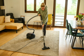 Fototapeta premium Young woman cleaning her home, making the bed, wiping glass surfaces, vacuuming and dusting. Housekeeping routine, cleanliness, home care, everyday domestic lifestyle