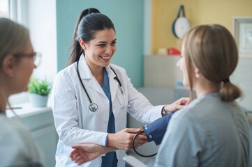 Fototapeta premium Friendly medical assistant checks visitor’s blood pressure in bright welcoming healthcare setting
