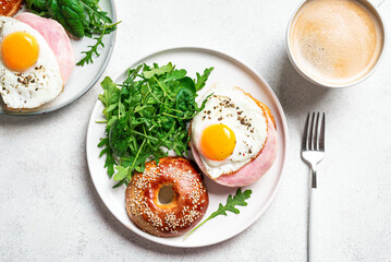 Healthy breakfast. Bagels with fried egg, ham and greens