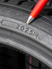 Close-up of tire date code with pen pointing to week and year marking on rubber sidewall