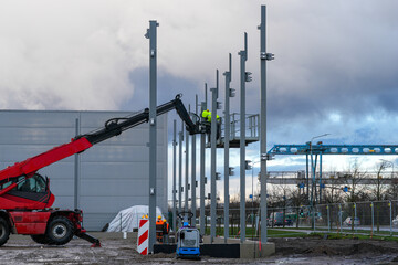 Workers installing steel columns with telescopic handler at industrial construction site