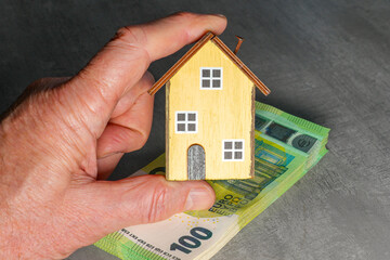 Hand Holding Small Wooden House on Euro Banknotes , Concept of Home Financing and Real Estate Investment