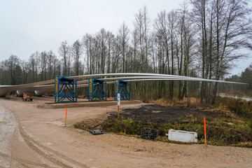 Wind turbine blades stored on support racks at construction site near forest during installation