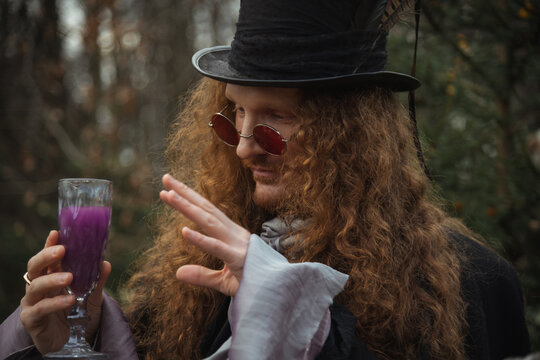 Man in black attire holds purple drink in forest setting during fall