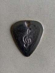 Silver guitar pick with engraved treble clef