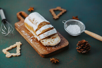 Sliced bread dusted with sugar on wooden board with whisk and pine cone