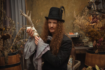 Fototapeta premium Man with long hair holding an antler skull in a stylish room