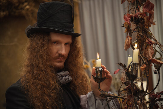 Mysterious man with long hair and candles at a spooky gathering