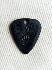 Black guitar pick with embossed treble clef symbol