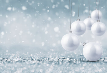 White Christmas ornaments hanging over a frosty winter background with snow and bokeh lights. Elegant holiday decoration scene in cool silver tones, perfect for festive seasonal designs