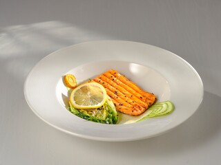 A grilled salmon fillet glistens on a white plate, artfully arranged with a lemon slice and green salad. The dish showcases culinary skill and a passion for taste