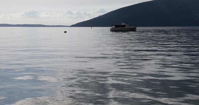 Empty beach at seaside at early autumn, Boka bay, Adriatic sea, Montenegro, Mediterranean, waves flushing concrete beach on cloudy day