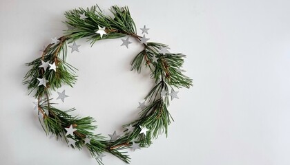 Natural pine needle wreath on a white background with silver glitter stars, concept card and cteative background