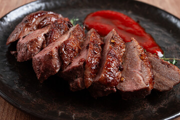 roast duck breast, sliced on a plate, with red sauce, homemade, no people,