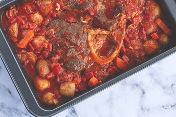 ossobuco stew with vegetables, knuckle on the bone with new potatoes, in tomato sauce,homemade, top view, no people,