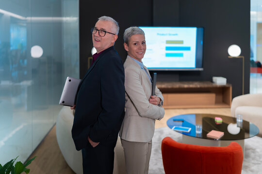 Business colleagues standing back to back showing confidence