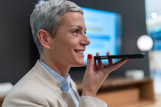 Mature woman using voice assistant on smartphone