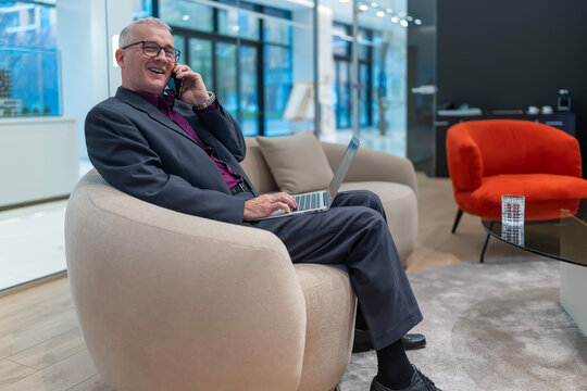 Mature businessman communicating and working remotely in office lounge