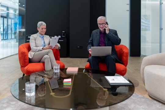 Business colleagues collaborating networking with technology in office lounge