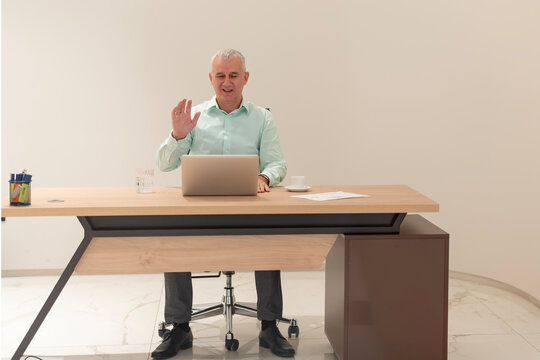 Mature businessman waving from laptop during video call