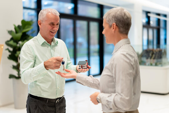 Real estate agent handing over house keys and model