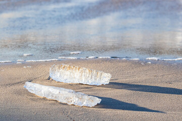 Two ice blocks washed ashore on sandy beach with shadows © Kersti Lindström