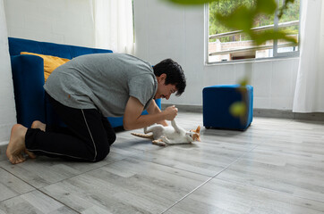 Relaxed man on the living room floor interacting and playing with his cat, a warm and everyday scene at home. Concept of companionship and cozy moments at home
