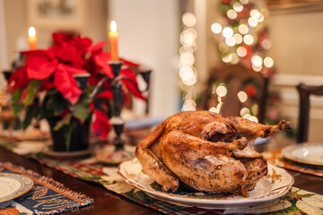 Holiday roasted turkey served on a festive Christmas table with candles, poinsettias, and warm bokeh lights, traditional for Christmas and Thanksgiving in the USA.
