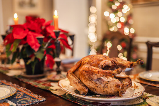 Holiday roasted turkey served on a festive Christmas table with candles, poinsettias, and warm bokeh lights, traditional for Christmas and Thanksgiving in the USA.