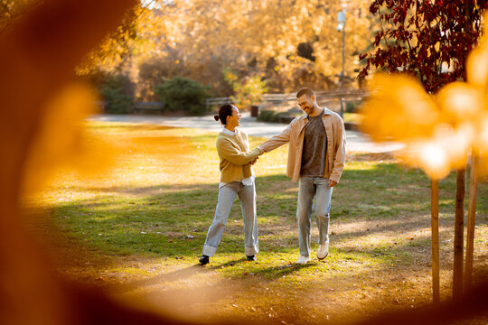 Autumn walk in the park with a Korean woman and Caucasian man amidst colorful leaves - Powered by Adobe