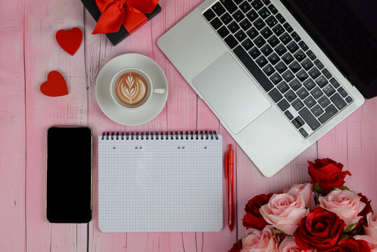 Laptop computer and an open heart-shaped gift box on a dark wooden table against a background of lights. Online shopping and chatting, virtual Valentine's Day, love in time COVID-19 concept.