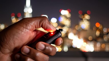 Hand Pressing Remote Shutter Release Button to Graph City Skyline