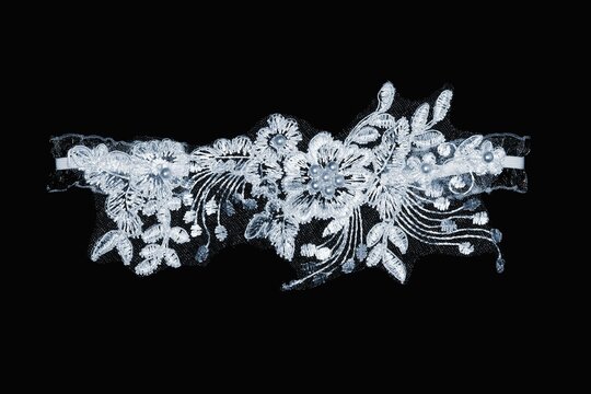 Women's wedding white lace garter on a black background.
