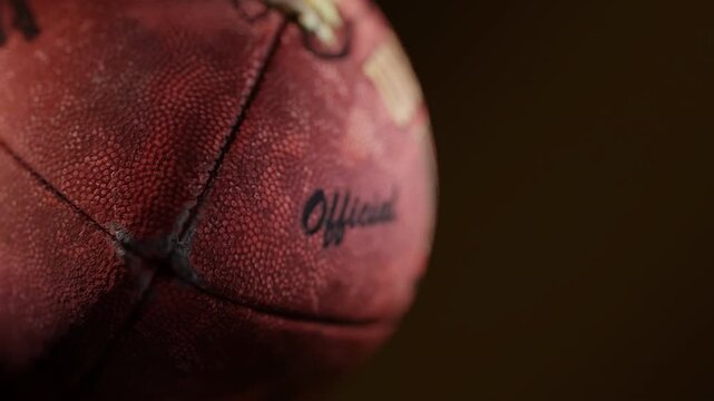 A close-up American football rotates in a seamless loop, dramatic lighting revealing textured leather and sharp shadows. Cinematic, atmospheric, and ideal for intense sports intros or backgrounds.