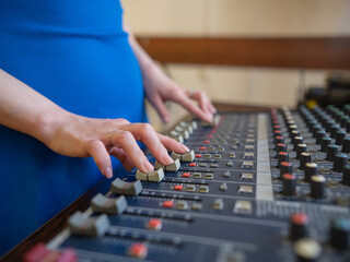 Hands Adjusting Sound Levels on Mixing Console.