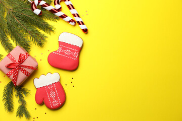 Tasty gingerbread cookies and Christmas decor on yellow background, flat lay. Space for text