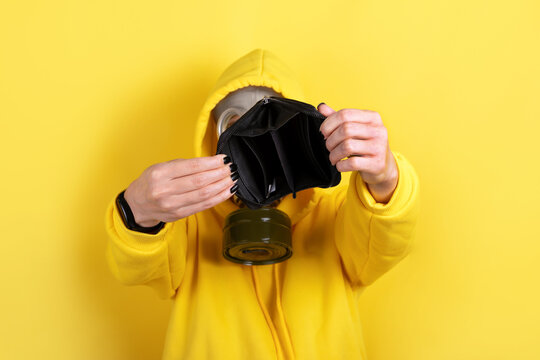 Person in yellow hoodie and gas mask holding open empty wallet against yellow background, illustrating financial crisis or economic stress. - Powered by Adobe
